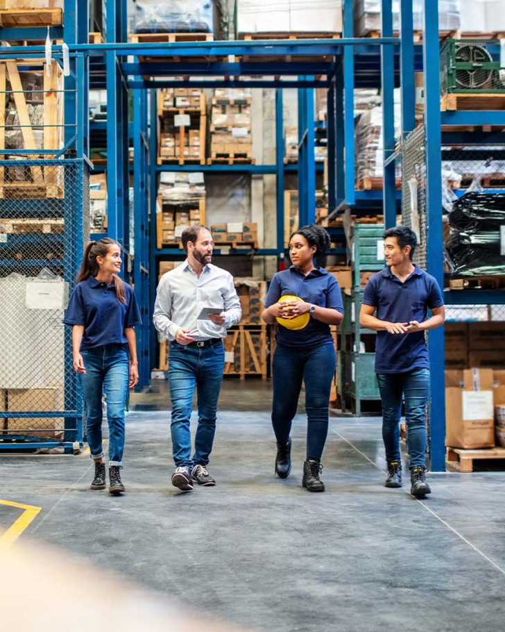 Warehouse employees walking and talking down aisle