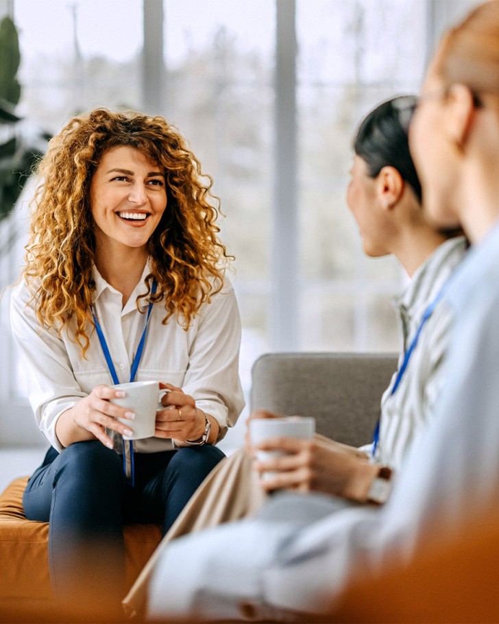 Smiling colleagues casually chatting while sitting on a sofa in the office break room
