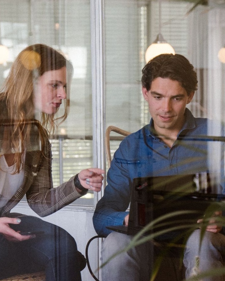 Colleagues discuss a project using their laptop