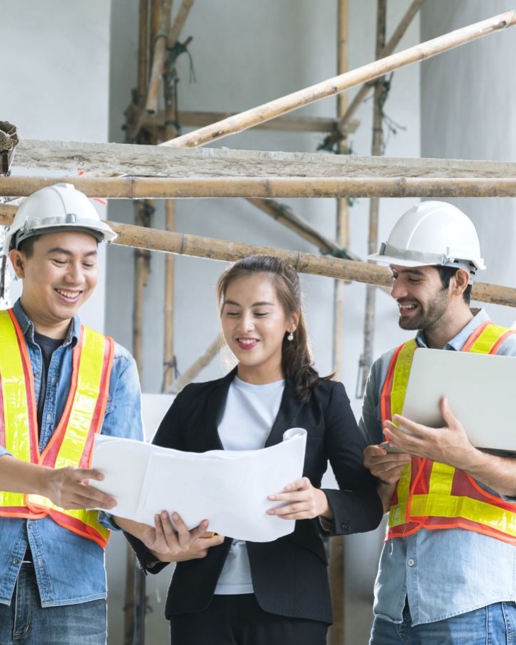 Three colleagues go over plans in a construction site