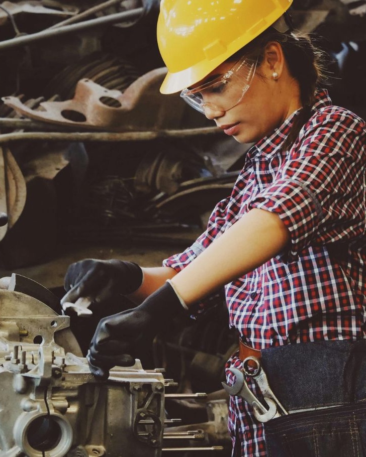 Technician repairing machinery in a workshop, surrounded by spare parts