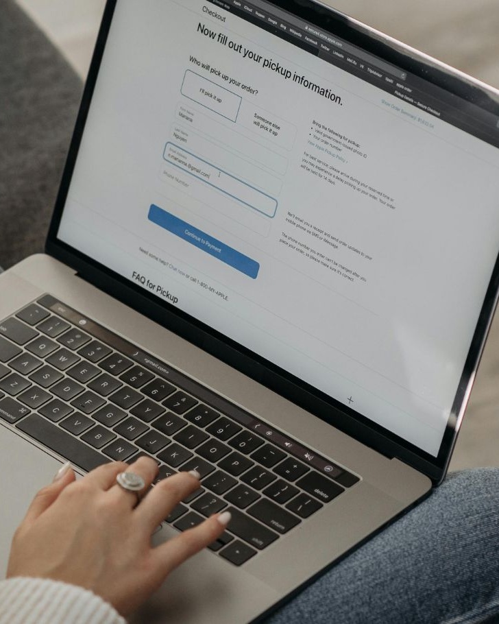 Person holding a credit card while filling out an online checkout form on a laptop, illustrating modern e-commerce.