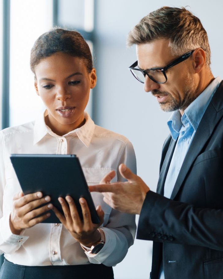 Coworkers have a discussion while looking at their tablet