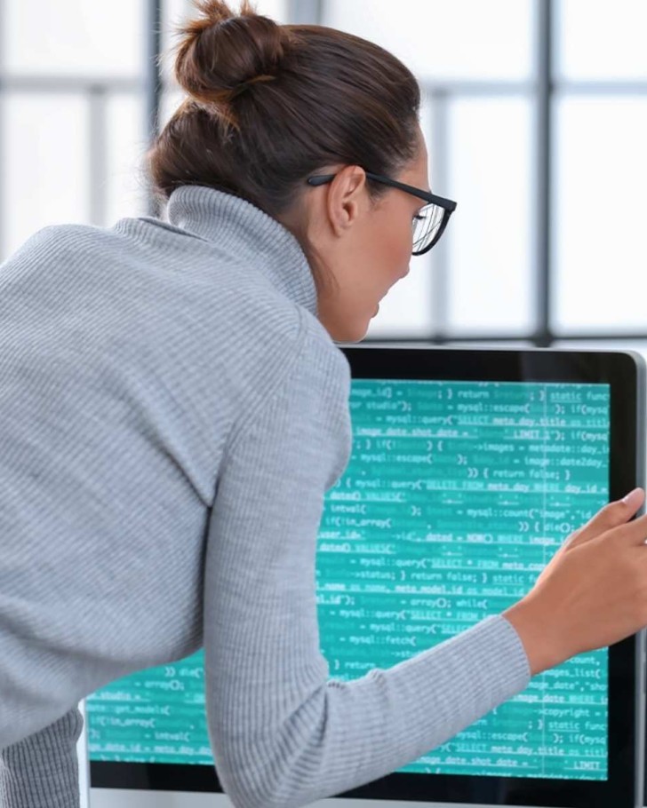 Woman examining data and code on two computers