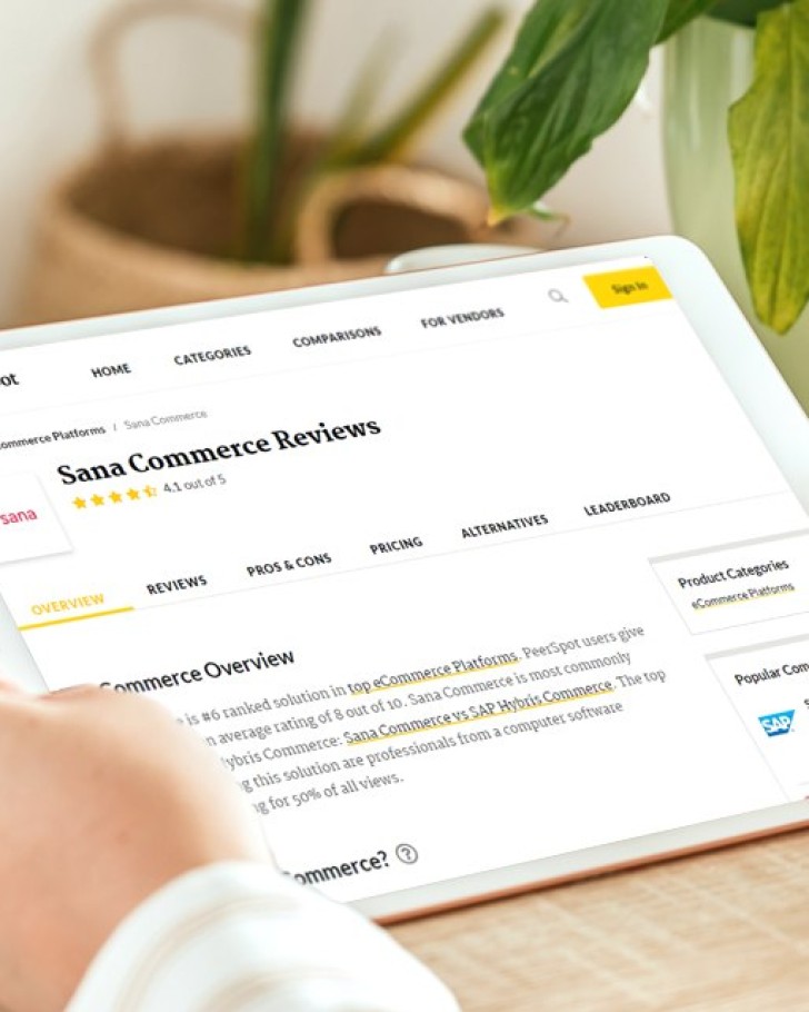 Person holding tablet and reading Sana Commerce reviews on review platform PeerSpot - featured image