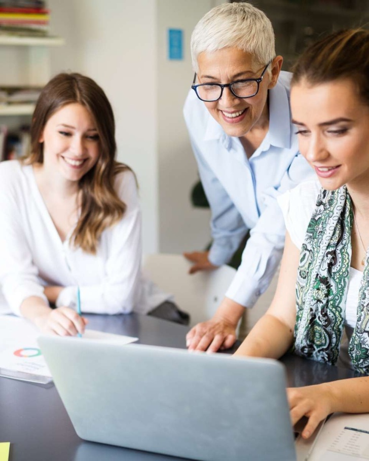three women looking at a computer and evaluating business choices