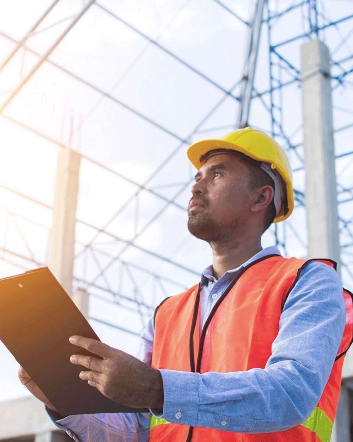 Man working in construction holds clipboard