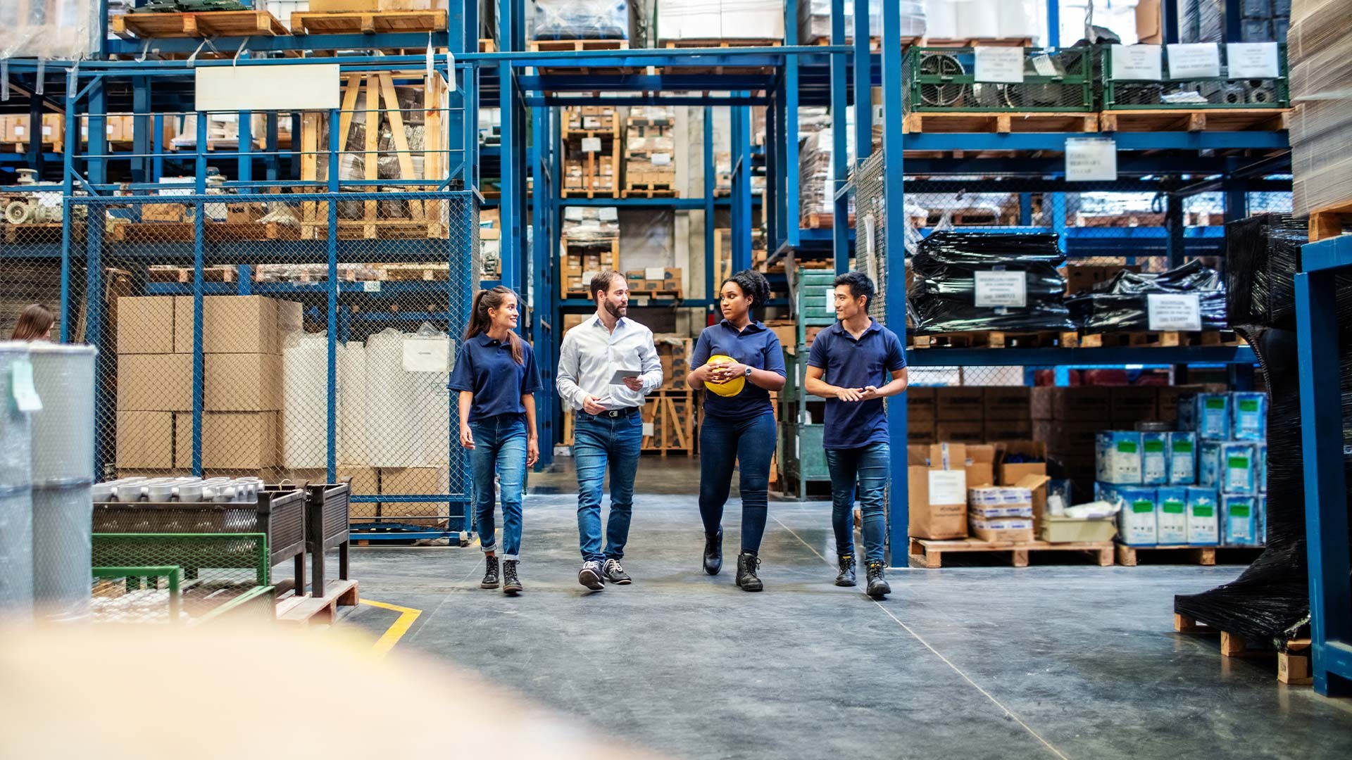 Warehouse employees walking and talking down aisle