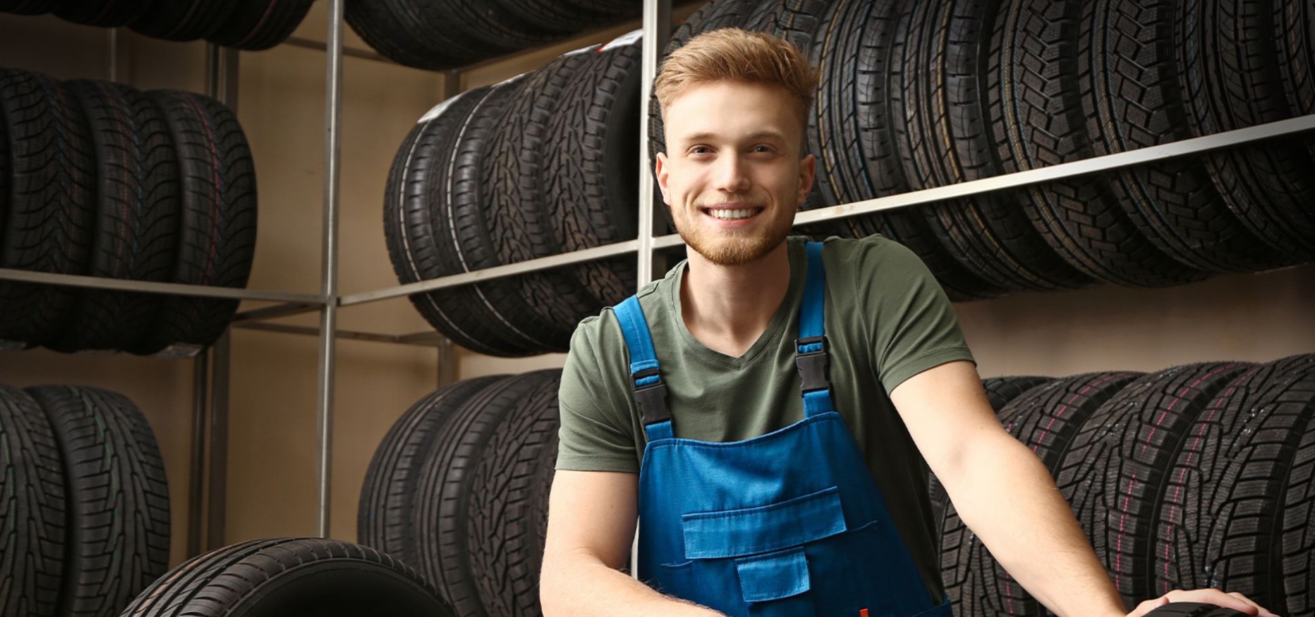 Man working in automotive industry smiles in a tire warehouse
