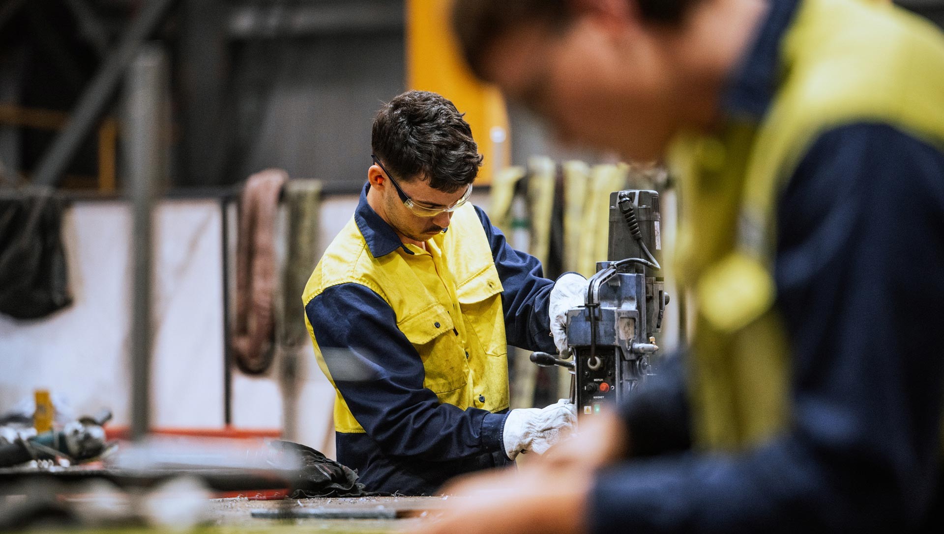 Qualified welders working on steel construction, grinding and welding iron parts in modern bright warehouse