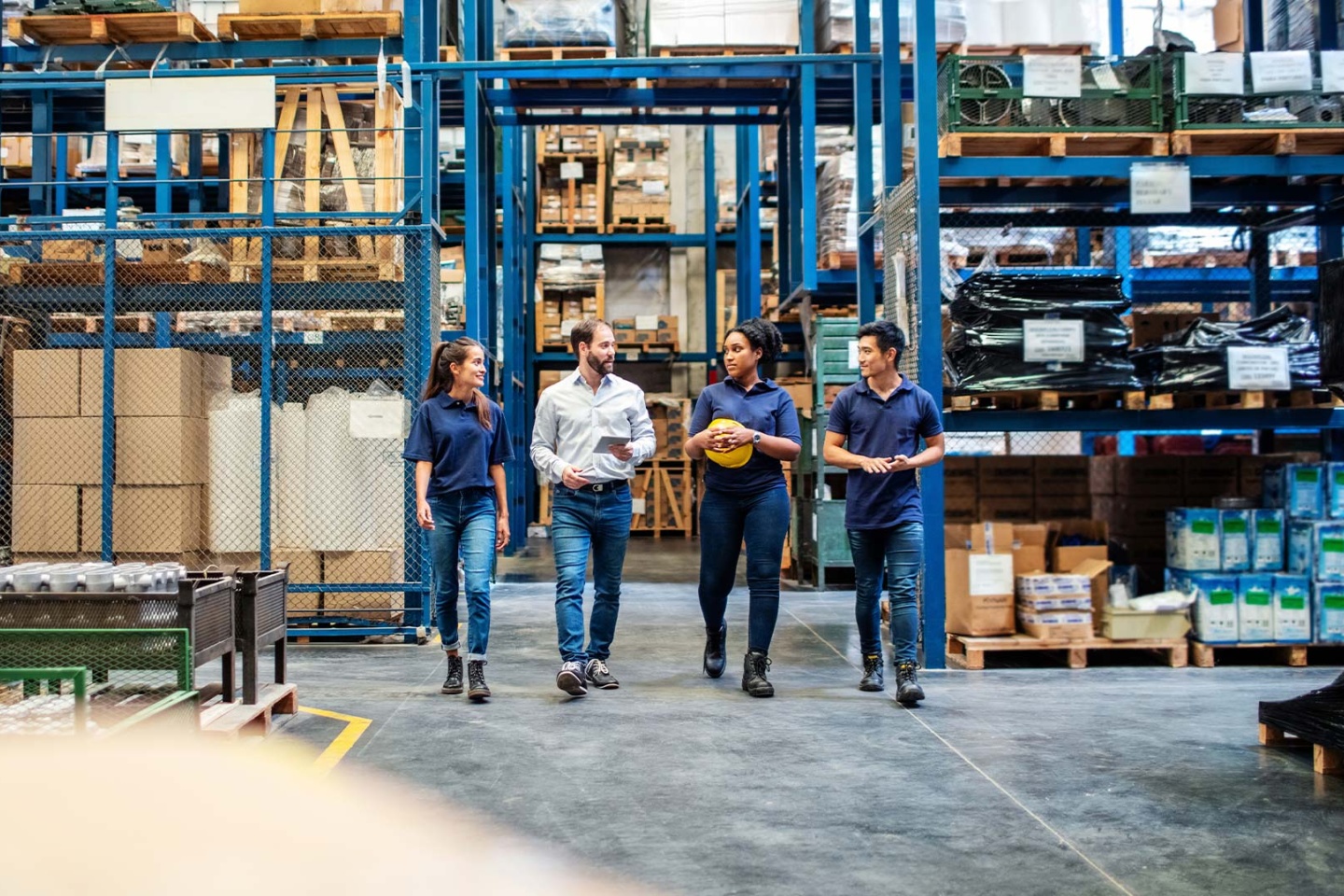Warehouse employees walking and talking down aisle