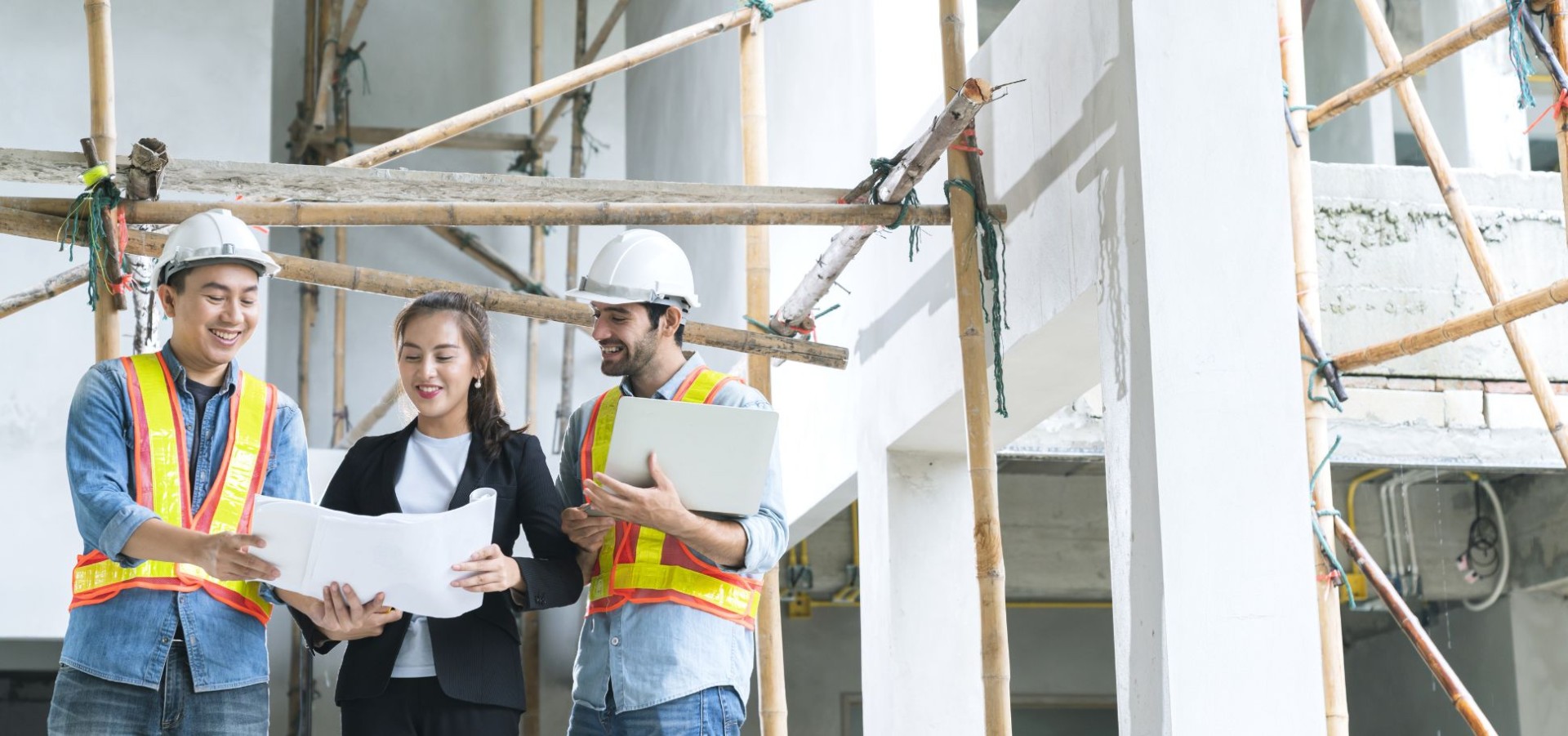 Three colleagues go over plans in a construction site