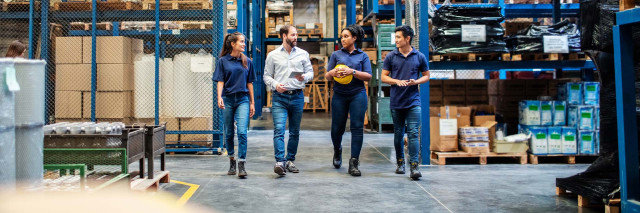 Warehouse employees walking and talking down aisle