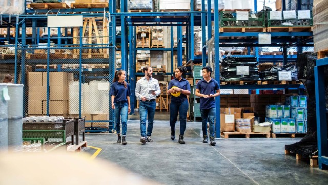 Warehouse employees walking and talking down aisle