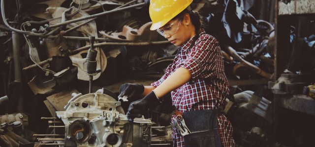 Technician repairing machinery in a workshop, surrounded by spare parts