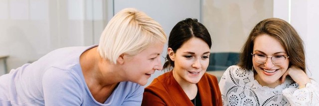 Three women colleagues discuss work over laptop