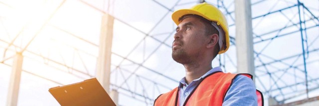 Man working in construction holds clipboard