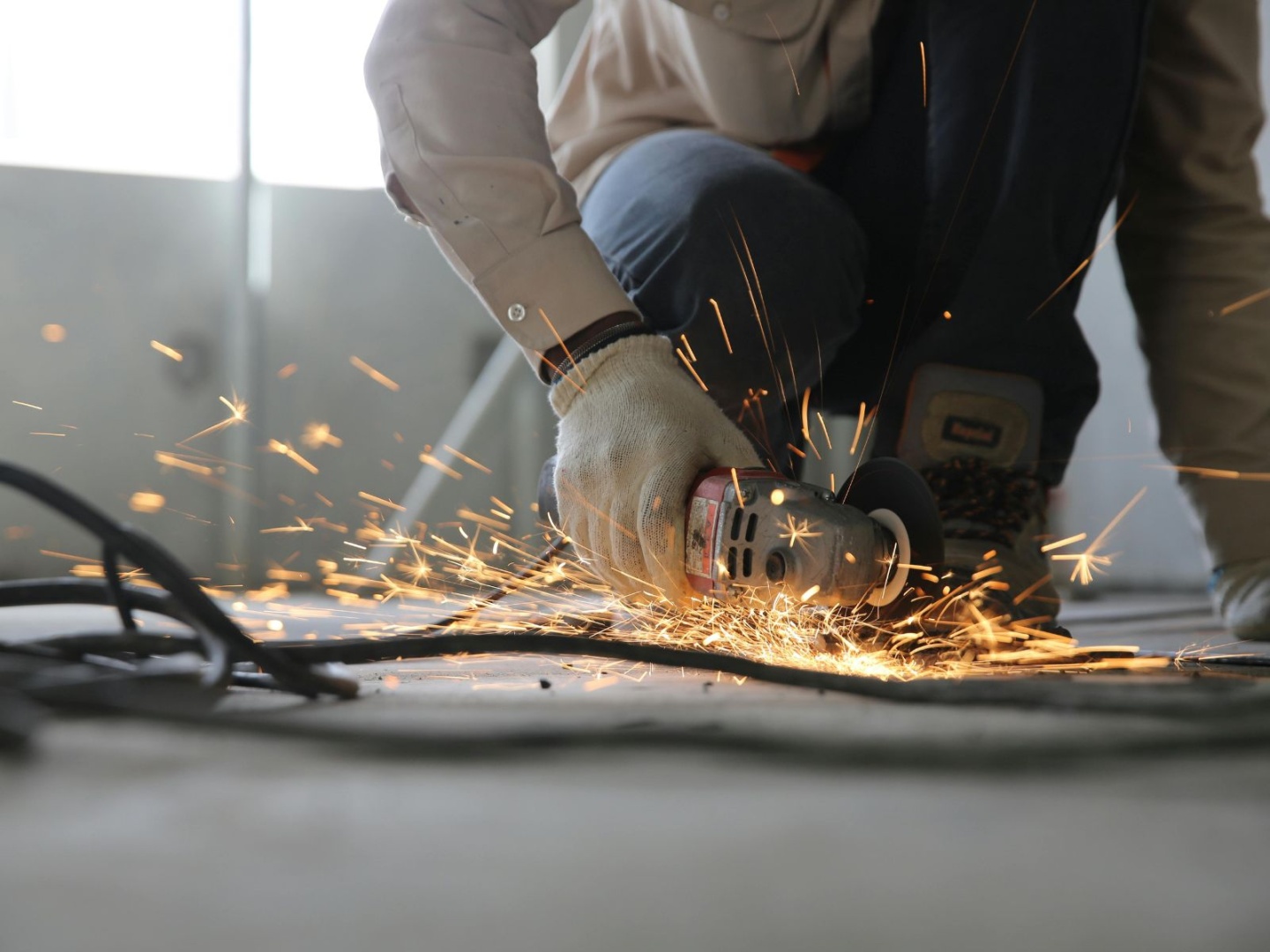 Worker using an angle grinder to cut metal