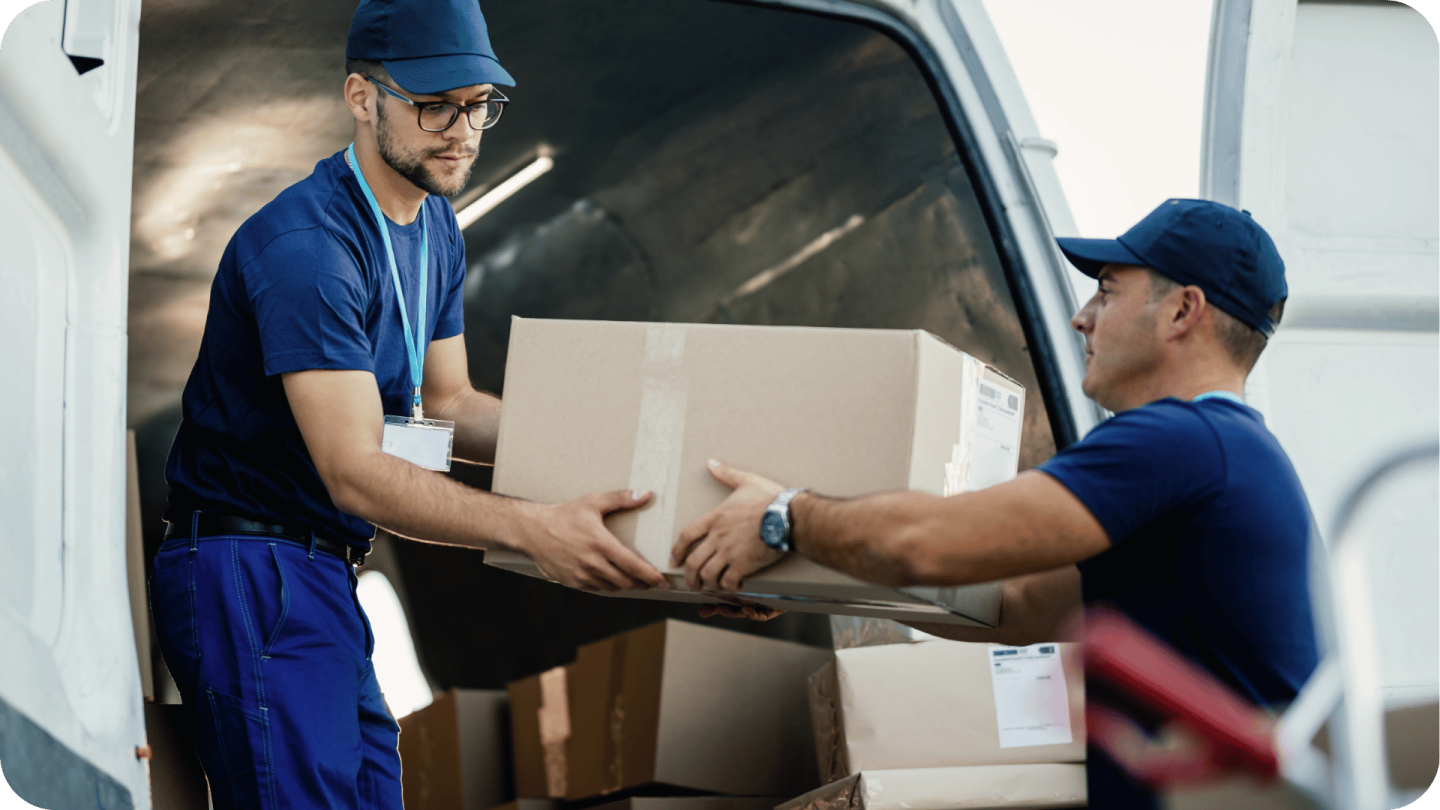Young couriers cooperating while unloading packages from delivery van.