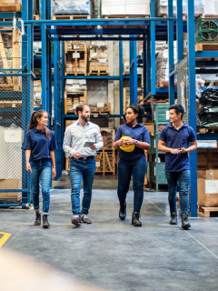 Warehouse employees walking and talking down aisle