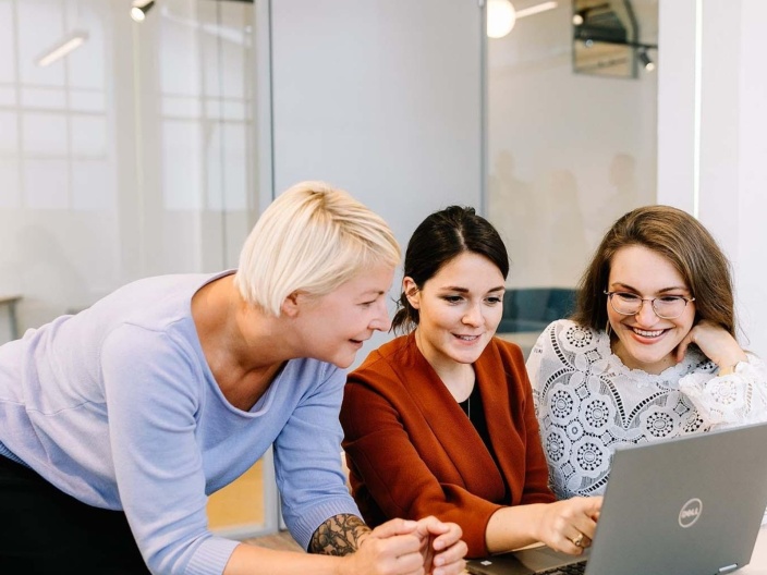 Three women colleagues discuss work over laptop