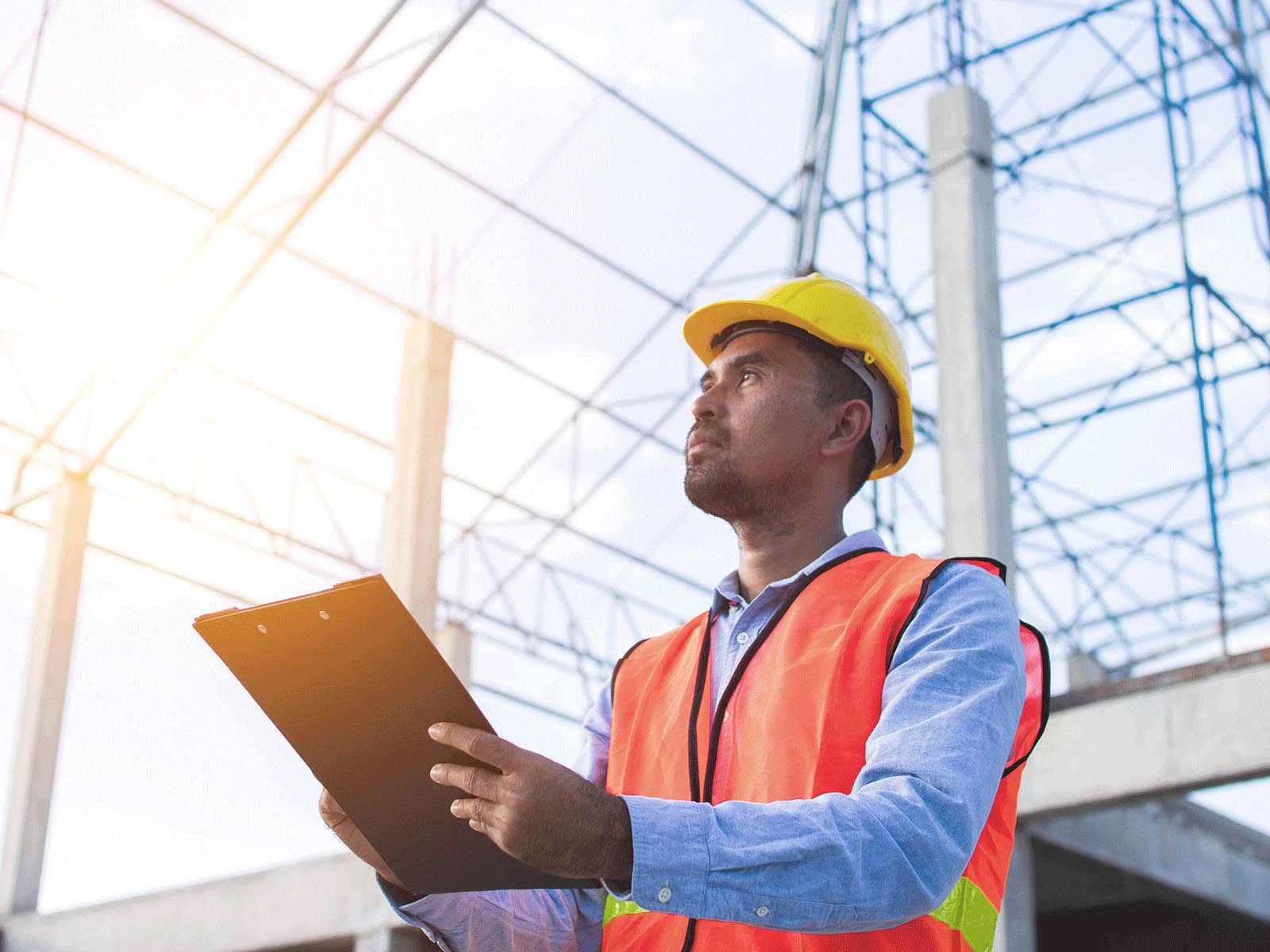 construction man holding clipboard looking up