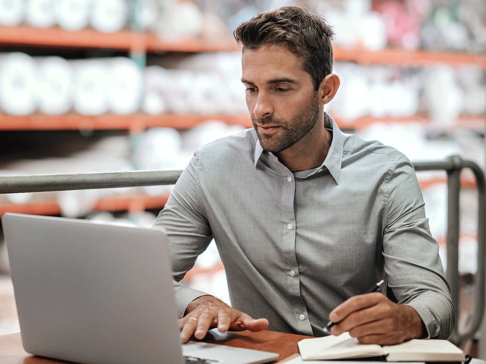 Man working on laptop in warehouse