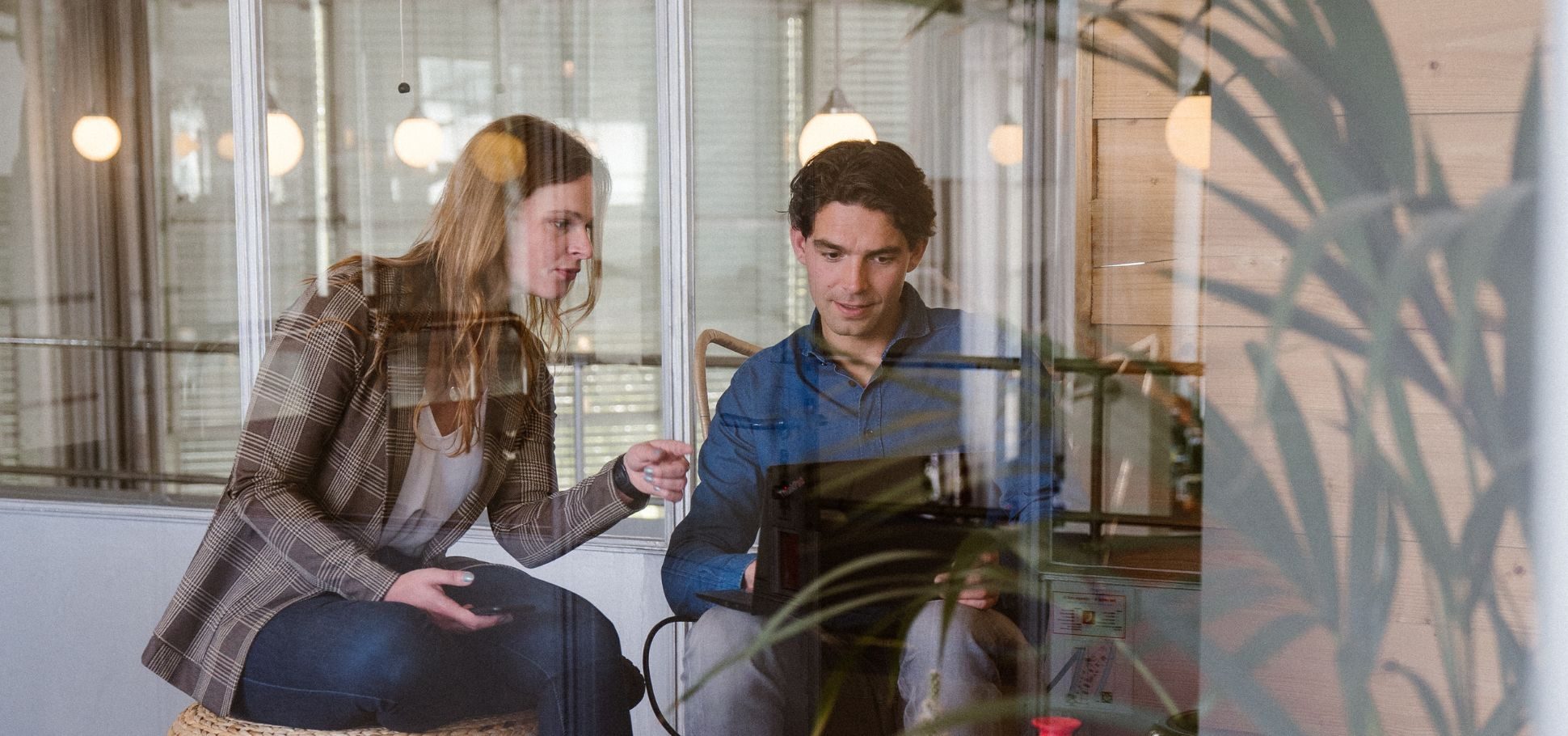 Colleagues discuss a project using their laptop