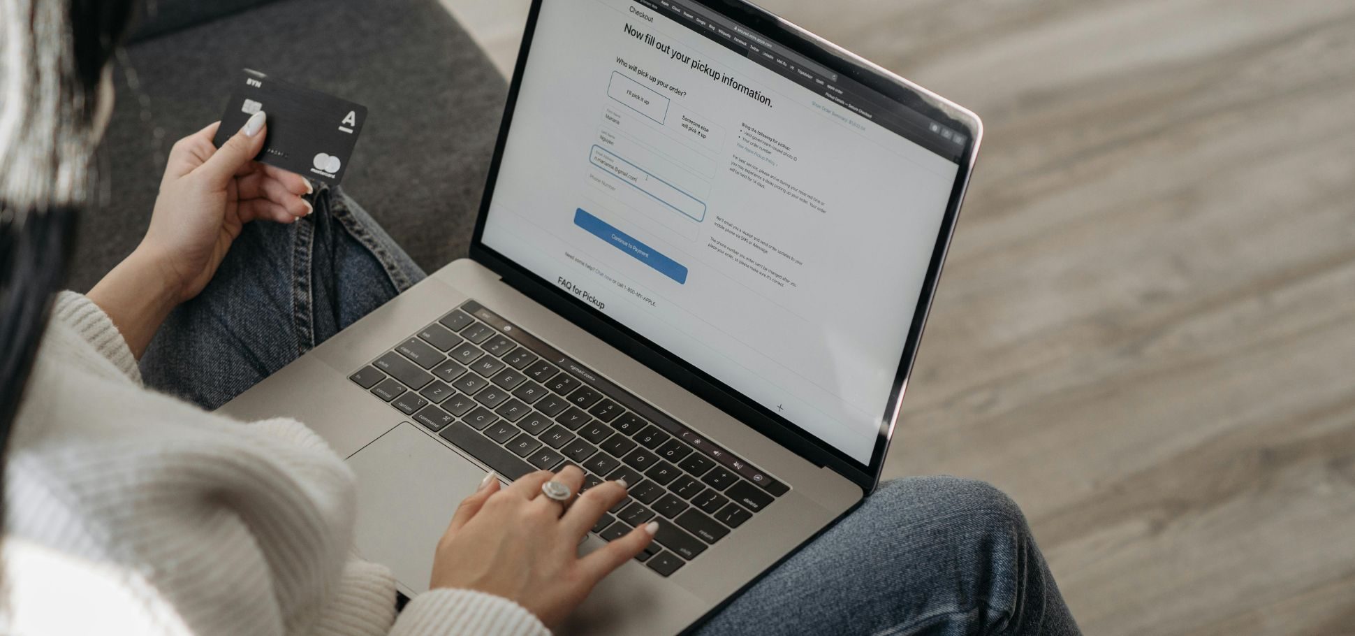 Person holding a credit card while filling out an online checkout form on a laptop, illustrating modern e-commerce.