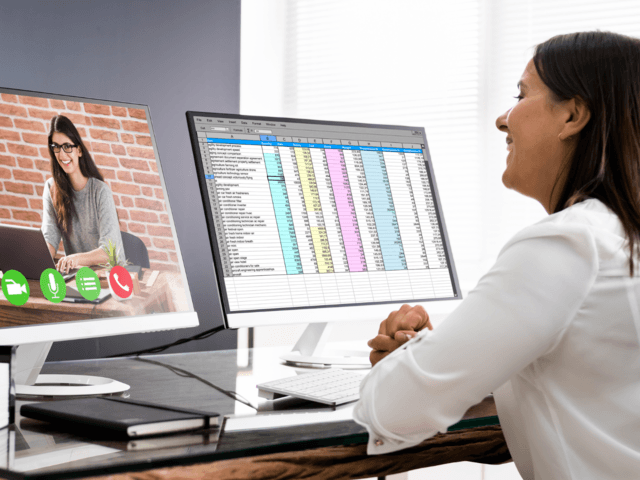 a woman with a spreadsheet open on one monitor and a video call with another woman on the other monitor
