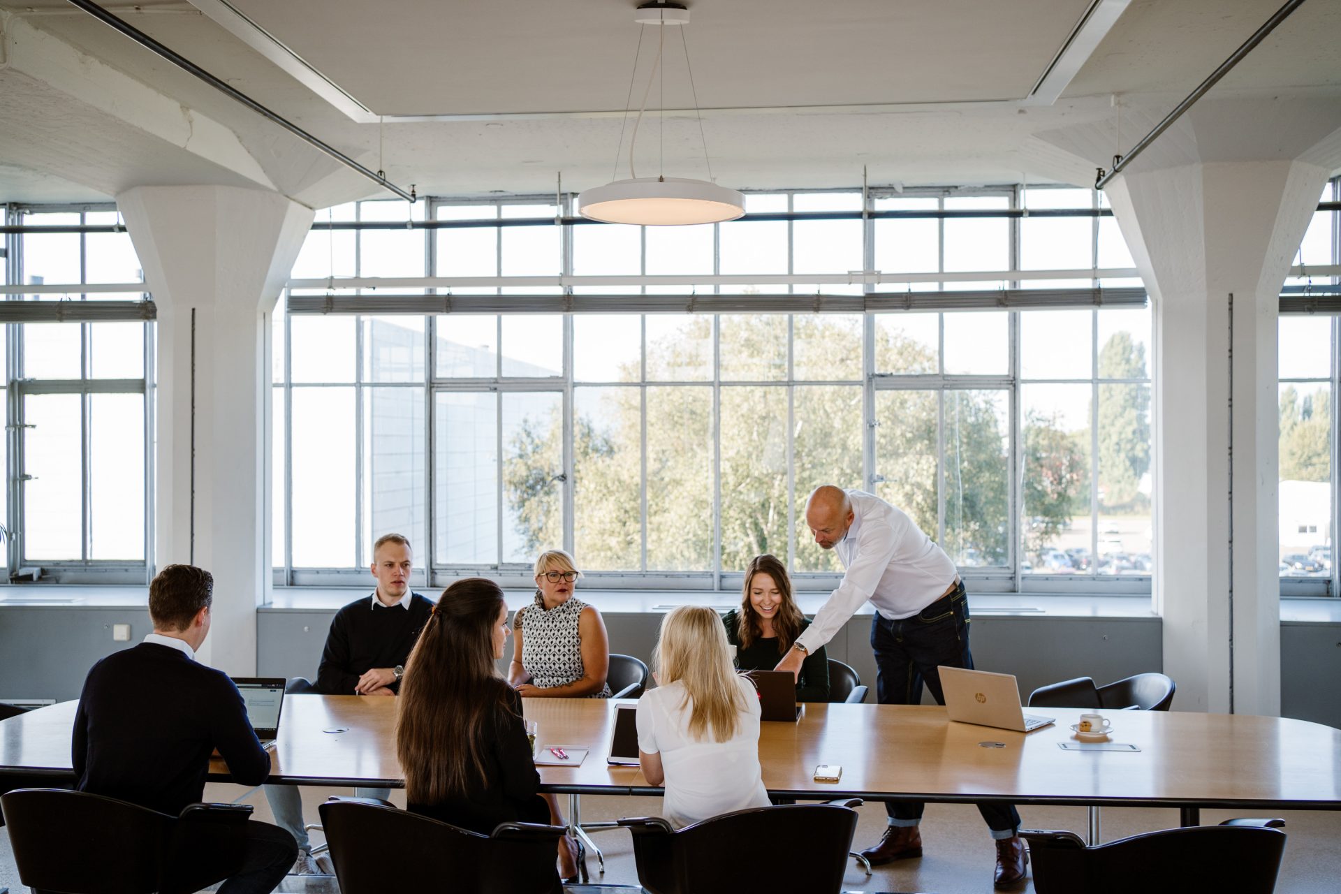 Teammitglieder sitzen am Konferenztisch und ein Mitarbeiter zeigt etwas auf dem Laptop - Blog b2b kunden von heute