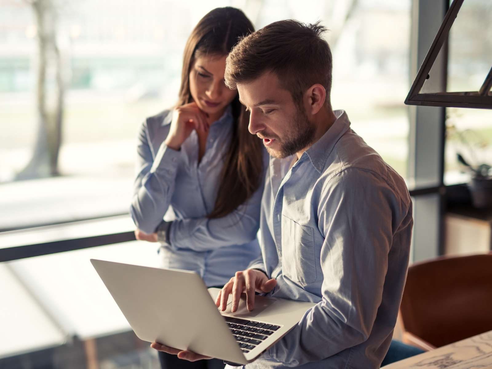 Zwei Fachkräfte besprechen Daten an einem Laptop in einem hellen Büro – Zusammenarbeit an einem digitalen Projekt.