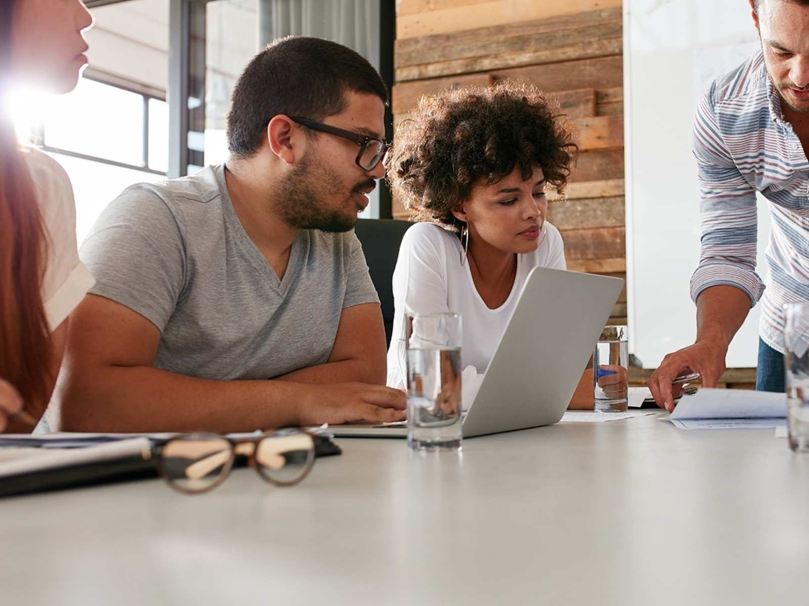 Group of colleagues huddled over a desk discussing a project