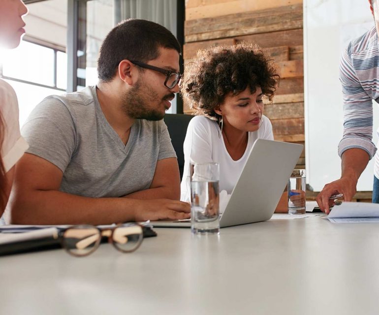 Group of colleagues huddled over a desk discussing a project