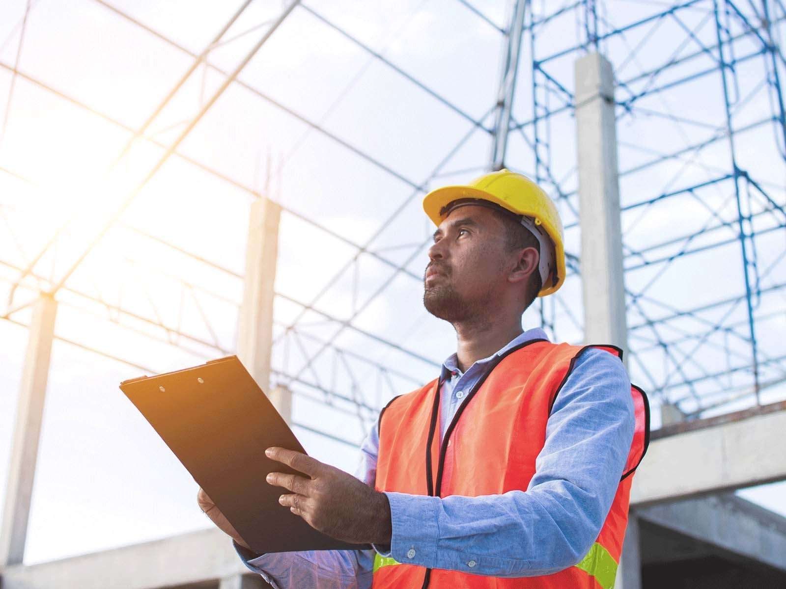 Man working in construction holds clipboard